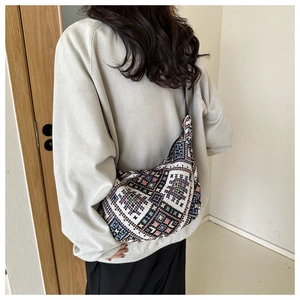 Detailed view of bohemian ethnic knit canvas bag with geometric patterns on model