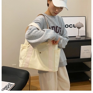 Detailed side view of canvas tote bag with pink straps and convenient side pocket