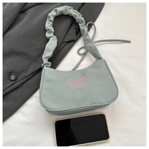 Détail du sac en nylon vert menthe avec bandoulière froncée et papillon rose brodé