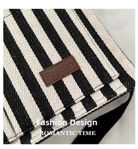 Detail of black and white striped canvas tote with brown leather fashion label