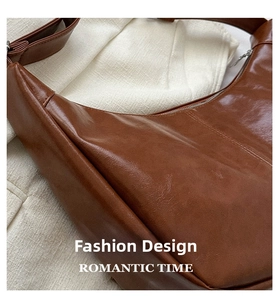 Detail view of the caramel brown crescent bag showing high-quality leather texture and zipper