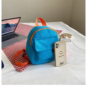 Mini sac à dos en toile bleu et orange à côté d'un smartphone pour comparer la taille