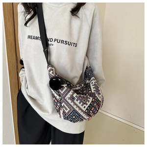 Detail of bohemian canvas crossbody bag with geometric embroidery and plush pom-pom charm