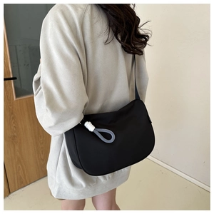 Detail view of black nylon crescent bag with adjustable strap and braided cord accent