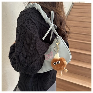 Détail du sac sous le bras plissé bleu clair avec broderie papillon et breloque en peluche