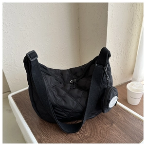 Detail of black quilted hobo bag with mini pouch on a stylish wooden tray setup