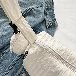 White quilted nylon dumpling crossbody bag with mini pouch and blue denim background