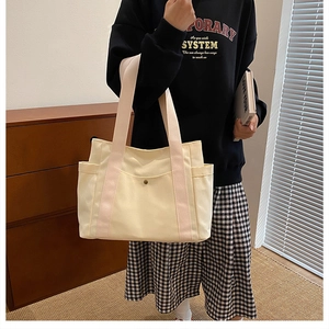 Detail of canvas tote bag with pink straps and front snap pocket in lifestyle setting