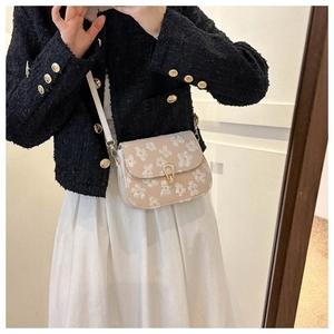 Detail of floral embroidery and gold twist lock closure on beige crossbody square bag