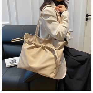 Detail of beige tote bag featuring stylish drawstring pleats and lightweight nylon texture