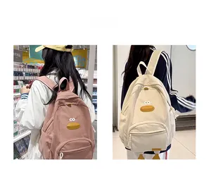 Detail of corduroy cartoon duck backpacks in pink and beige with cute 3D duck feet