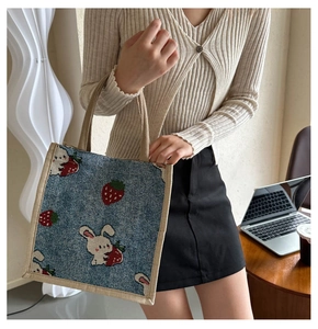 Detailed knit texture of a denim blue tote bag featuring a cute bunny and strawberry design