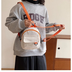 Détail du mini sac bandoulière en toile blanc cassé avec une sangle orange réglable