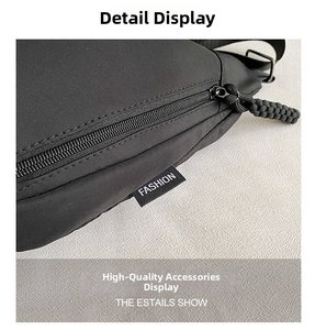 Detail of high-capacity oxford crossbody bag featuring zipper closure and fashion tag