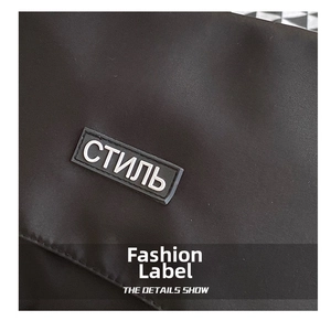 Detail of black nylon messenger bag featuring a stylish silicone patch with white text