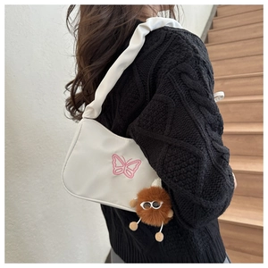 Détail du sac sous l'aisselle en nylon blanc avec broderie papillon et charm peluche