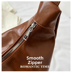 Close-up of smooth silver metal zipper and lychee grain brown PU leather on tote bag