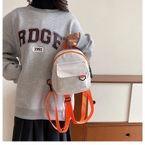 Vue latérale du mini sac à dos en toile blanc avec des bretelles orange sur le modèle