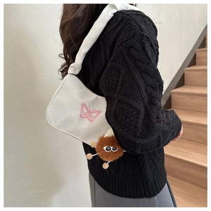 Détail du sac à bandoulière plissé blanc avec broderie papillon rose et pendentif