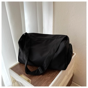 Vue détaillée du sac de voyage noir avec bandoulière réglable et poche zippée