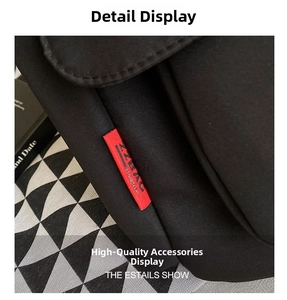 Close-up of black nylon messenger bag featuring a vibrant red brand label and stitching