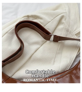 Detail of brown glossy leather shoulder strap with silver metal buckle and soft texture