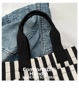 Close-up of durable black woven handles and vertical stripe canvas texture on a tote bag