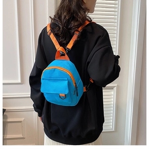 Détail du mini sac à dos en toile bleu vif avec bretelles orange porté par un mannequin