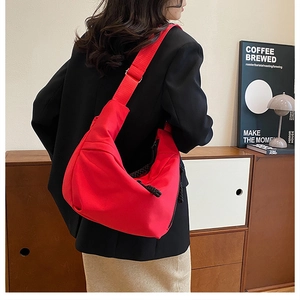 Close-up of red nylon crescent bag with wide strap in a minimalist lifestyle setting