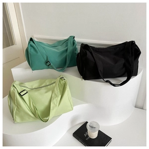 Three multi-colored cylindrical oxford cloth travel bags on white geometric steps