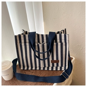 Close-up of striped canvas tote with adjustable strap and leather Fashion patch