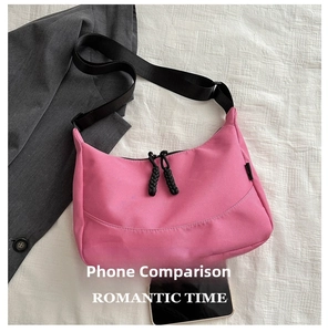 Pink waterproof nylon crescent tote bag with black adjustable strap and zipper detail