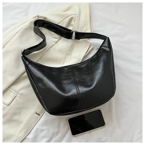 Gros plan du sac croissant en cuir noir brillant avec surpiqûres et boucle argentée