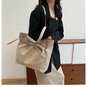 Detail view of beige waterproof tote bag featuring unique drawstring pleats and long strap