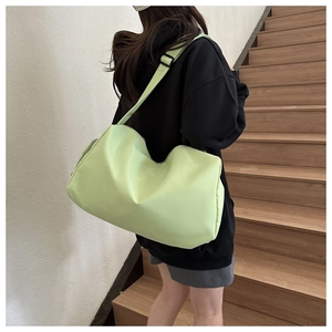 Close-up of vibrant neon green nylon sports bag worn across the back on a black hoodie
