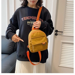Vue détaillée d'un mini sac à dos en toile jaune moutarde avec des bretelles orange vif