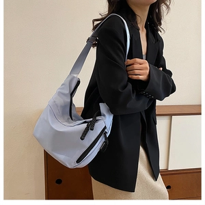 Detail of light blue nylon hobo bag with a zipper and stylish branded tag
