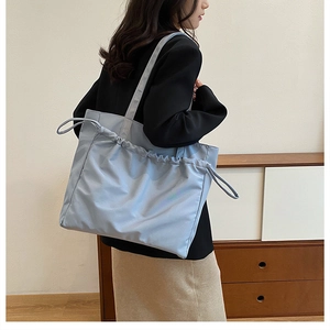 Detail of light blue tote bag with drawstring closure and soft pleated canvas texture