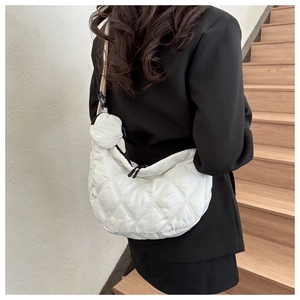 Detail of white quilted puffer crescent bag with a round coin purse and wide strap