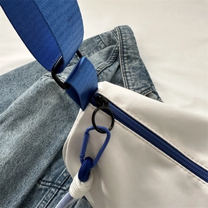 White nylon shoulder bag with blue zippers and sporty strap on denim background