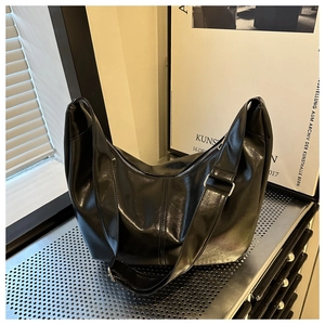 Détail d'un sac bandoulière en cuir PU brillant noir avec fermeture éclair argentée