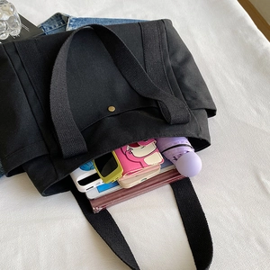 Large black canvas tote bag showing spacious interior with books and tablets for daily use