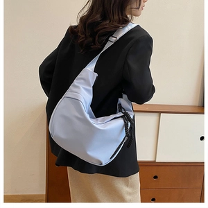 Detail of light blue nylon crescent bag with adjustable strap and woven zipper puller
