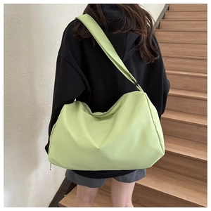Detail view of mint green nylon travel bag worn by model on stairs