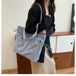 Detail of light blue waterproof tote bag featuring drawstring accents and wide shoulder strap