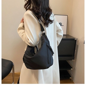 Detailed view of black nylon crescent crossbody bag with woven drawstring zipper pull
