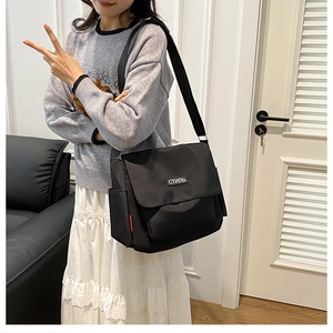 Detail of black nylon messenger bag with white СТИЛЬ text patch and side pocket