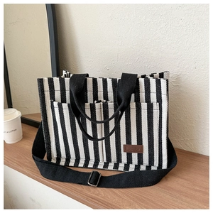 Detail view of striped canvas tote bag featuring front pockets and brown leather tag