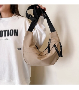 Close-up of khaki nylon hobo bag featuring an adjustable wide black strap and buckle