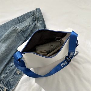 Minimalist white shoulder bag with contrast blue fashion strap shown in use